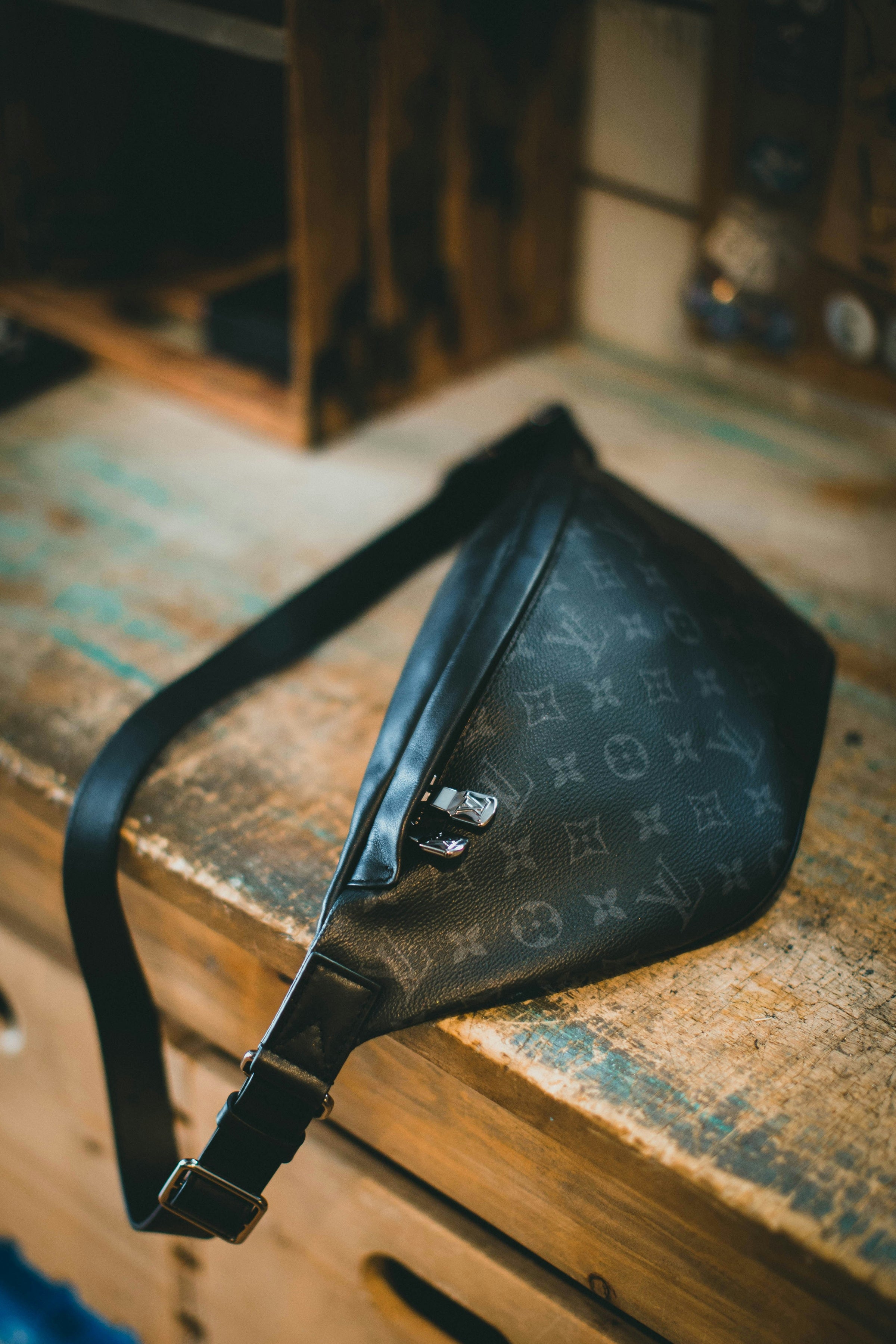 Sac banane Louis Vuitton Discovery en toile Monogram Eclipse posé sur un établi — sacs et portefeuilles homme GABY PARIS